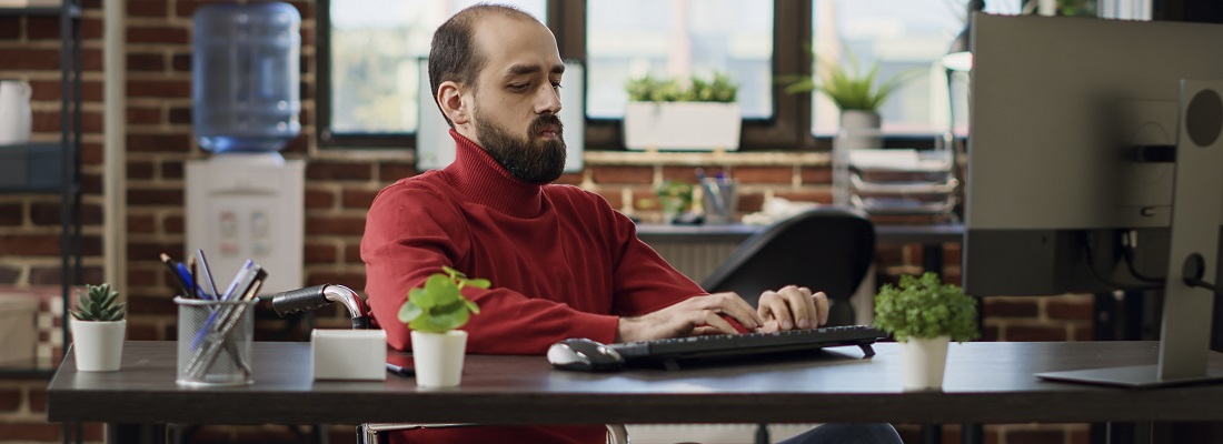 Una persona en silla de ruedas frente a un computador trabajando